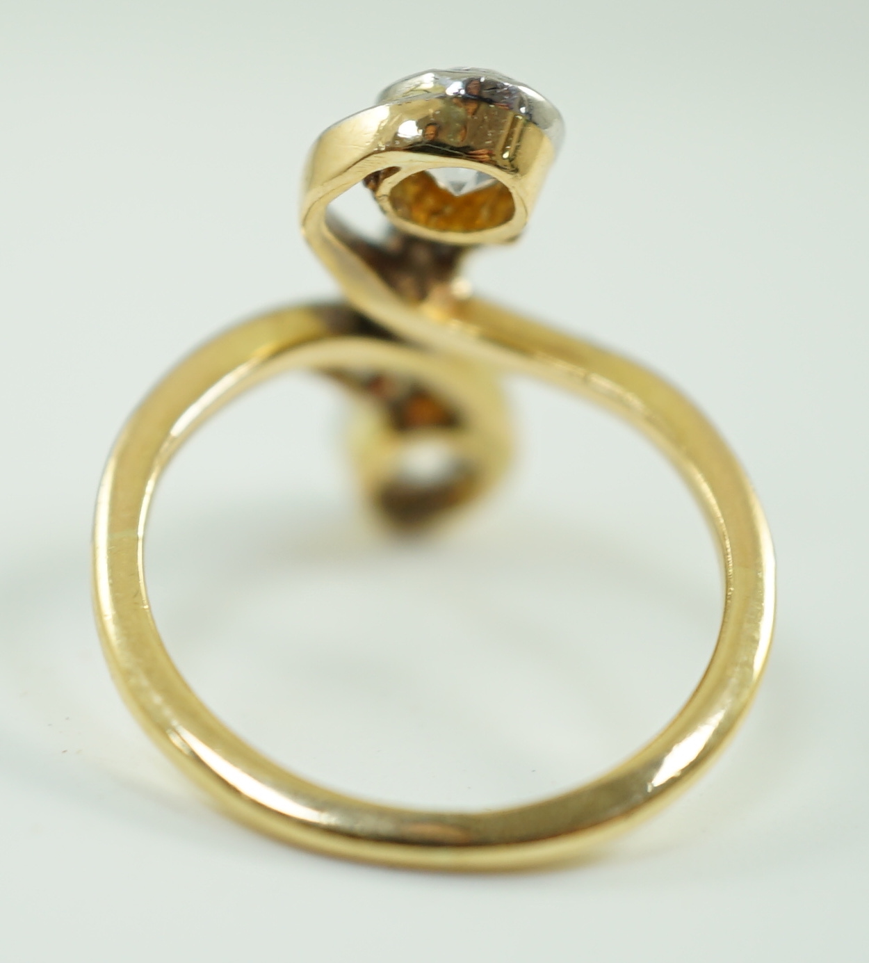 An early to mid 20th century gold and two stone diamond cross over ring, with five stone diamond chip setting